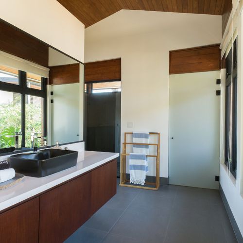 Luxury ensuite bathroom with floating hardwood vanity, black vessel sink and walk-in rainfall shower at Casa Oso luxury villa, Tamarindo.