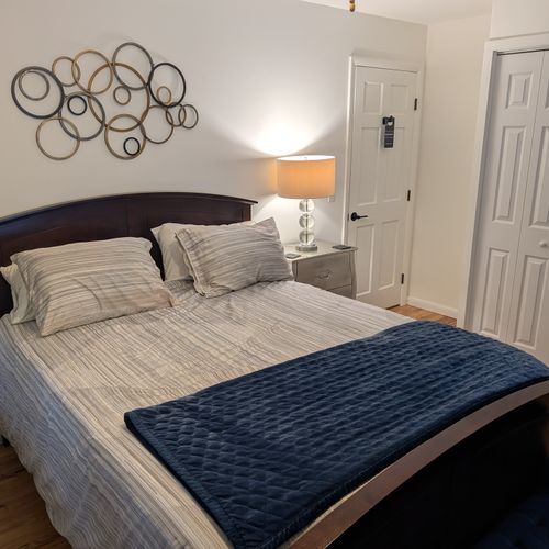 BEDROOM #3 (SECOND FLOOR):  Features a queen-size bed, nightstand, lamp, ottoman, chair, dresser, mirror, ceiling fan, closet, and private entrance to the backyard deck.