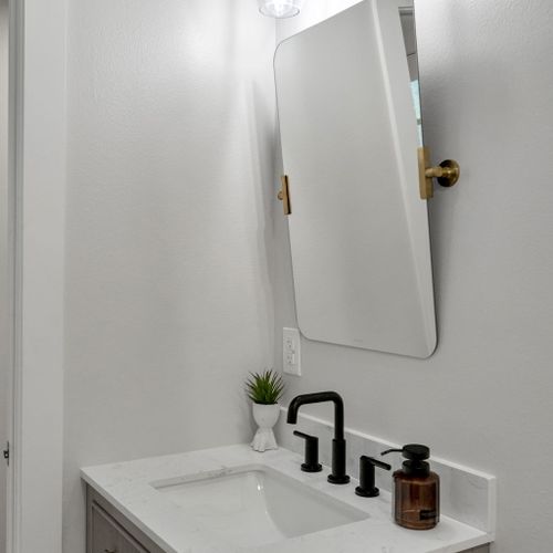 Get ready at the clean, bright vanity w/ a round mirror & modern black fixtures