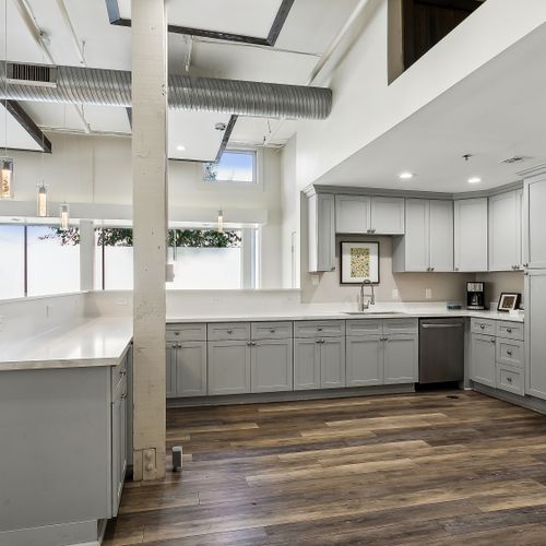 Sleek kitchen w/ gray cabinets, white counters & stainless dishwasher.