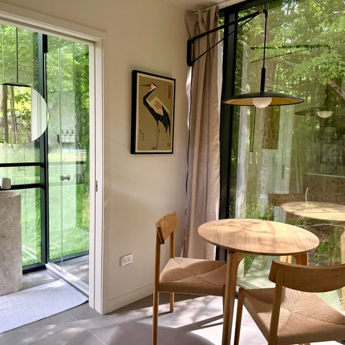 An airy dining corner flows toward the glass bath and the woods just beyond.