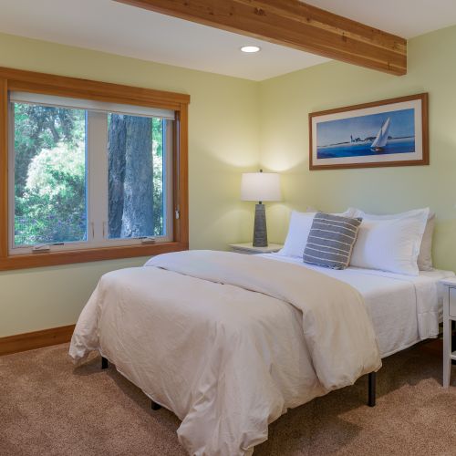 Relax in this inviting queen bedroom featuring plush bedding, soft lighting, and peaceful views of the surrounding greenery for a restful night's sleep.