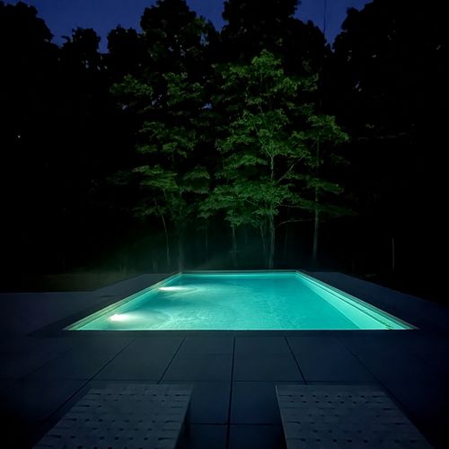 Slip into the glowing pool after dark, framed by softly lit trees.