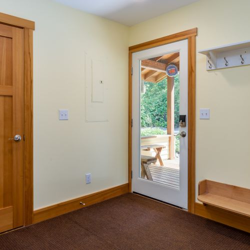 Step into a bright, functional entryway with coat hooks, a bench for shoes or bags, and direct access to the covered porch.
