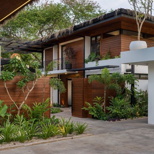 Open-air tropical courtyard breezeway between two palapa-roofed wings of Casa Oso luxury villa in Tamarindo, Costa Rica.