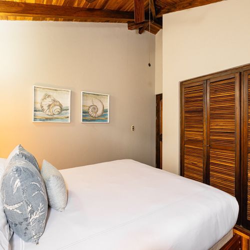 Guest bedroom — vaulted hardwood ceiling, nautilus and conch prints, slatted bamboo wardrobes.