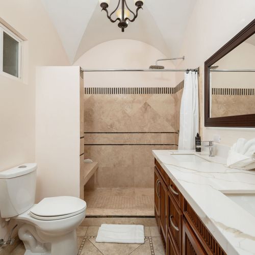 Spa-inspired master bathroom with walk-in shower and spacious layout at luxury Playa Langosta condo in Tamarindo, Costa Rica. Accessed through walk-in closet, featuring modern fixtures, natural light, tranquil design for peaceful relaxation.