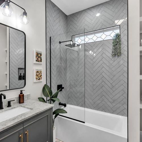 Refresh under the rainfall shower in this bright bathroom w/ herringbone tile & black fixtures