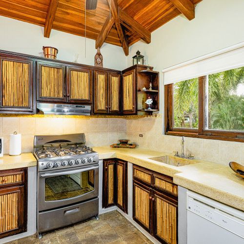 Casita kitchen with bamboo-fronted cabinets, gas range, granite counter and dishwasher at Casa Blue Lagoon, Tamarindo, Costa Rica.