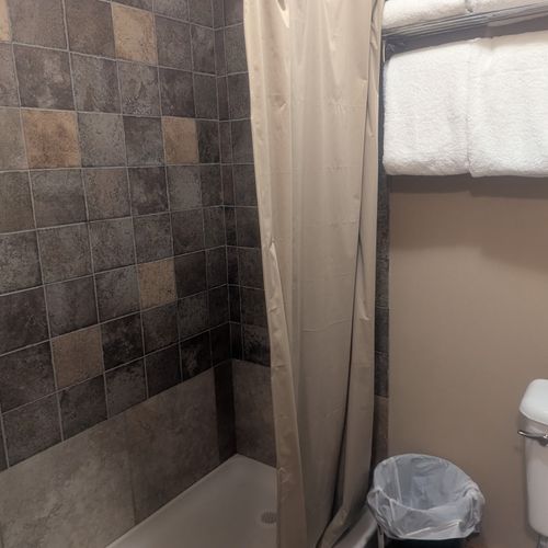 BATHROOM:  Features a shower and toilet.  (Note that there is no vanity, sink, or mirror in the bathroom.)