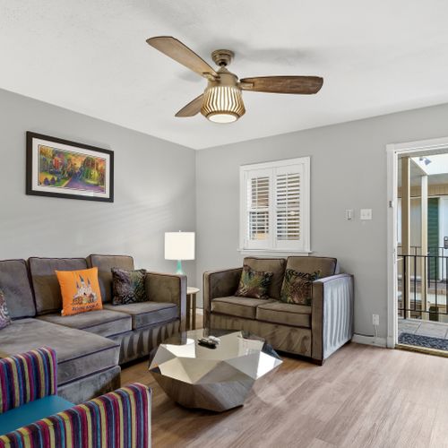 Airy living room w/ ceiling fan & entryway view
