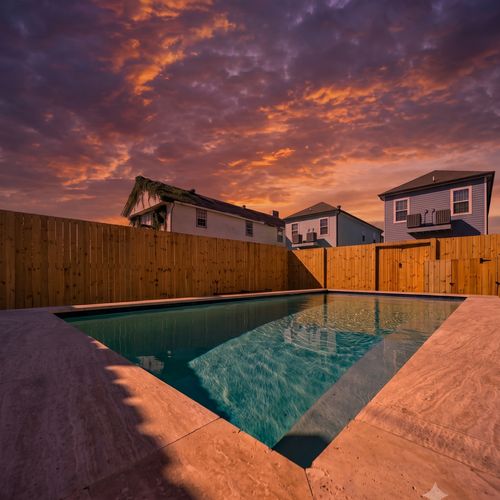 Sparkling pool enclosed by a wood fence — loungers & toys ready for a full day of fun.