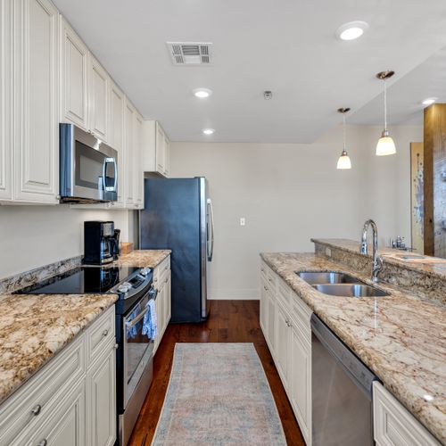 Galley kitchen stocked with stainless appliances