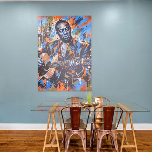 Glass dining table under vibrant portrait art