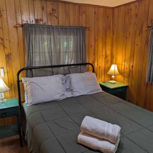 BEDROOM #1:  Includes a queen-size bed, nightstands, lamps, a dresser, and a mirror.