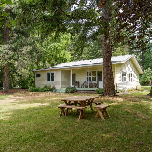 Unwind in a spacious yard surrounded by towering trees, with a picnic table perfect for outdoor meals, games, or relaxing in the fresh island air.