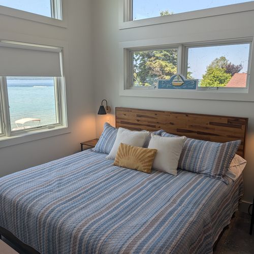 BEDROOM #3 (THIRD FLOOR):  Features a king-size bed, private mini-split A/C unit, ceiling fan, nightstands, reading lamps, chair, television, dresser, closet, private bathroom entrance, and spectacular views of Crystal Lake!