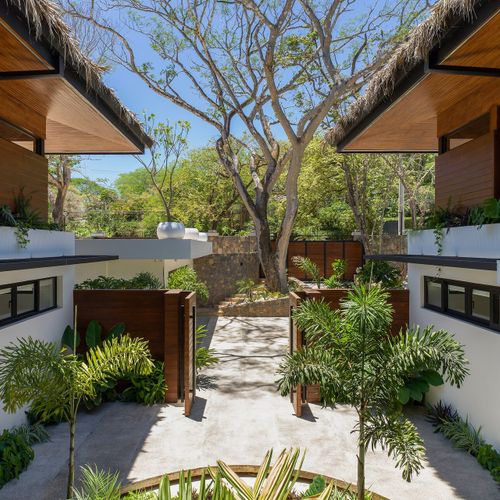 Private gated villa entrance with hardwood and white modern architecture and lush tropical landscape at Casa Oso, Tamarindo, Costa Rica.