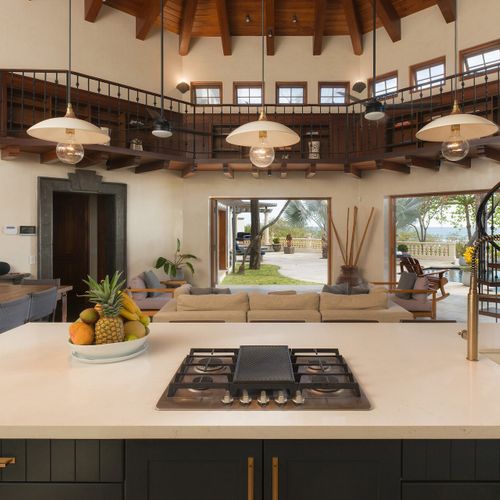 Great room from the chef island - iron mezzanine, spiral staircase, doors thrown open to the pool.