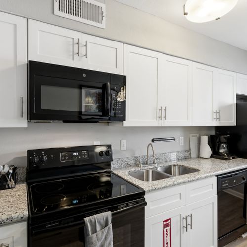 Fully equipped kitchen w/ black appliances & ample cabinet space for easy meal prep.