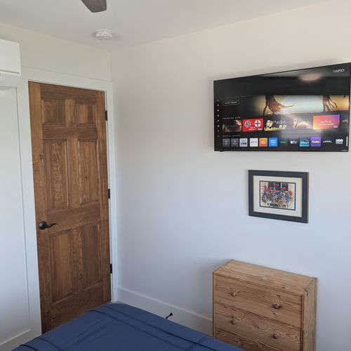 BEDROOM #1 (SECOND FLOOR):  Features a queen-size bed, nightstands, lamps, ceiling fan, mini-split A/C unit, television, dresser, closet, mirror, and a great view of Crystal Lake!
