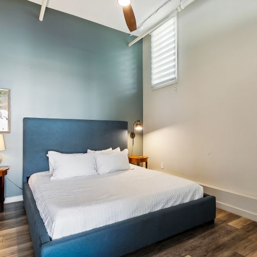 Serene bedroom w/ blue accent wall, bed & soft white linens.