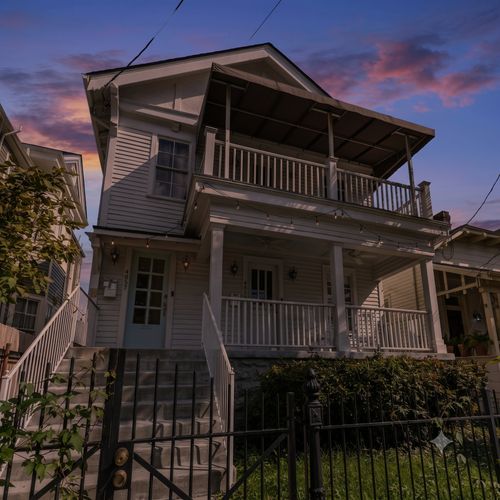 Charming two-story home w/ a wraparound balcony & lush surroundings.