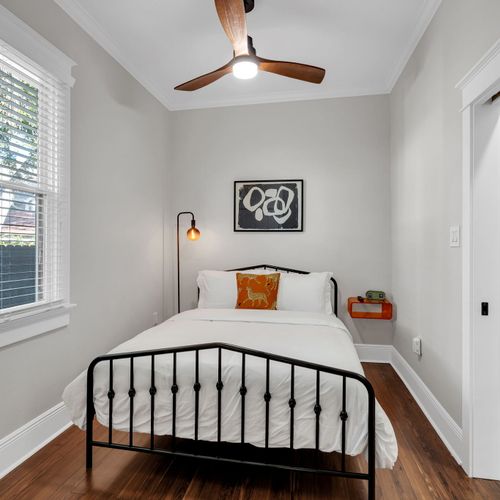 Charming bedroom w/ a classic iron bed, bold wall art & a reading light for winding down