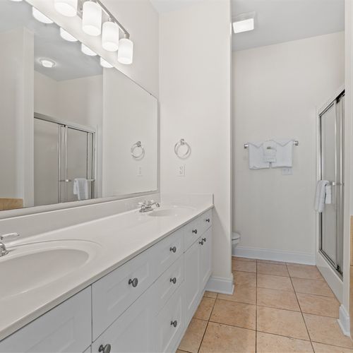 Full bathroom with double vanity, shower, and jacuzzi tub