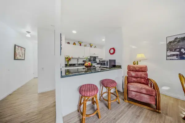 Bright kitchen breakfast bar with wooden stools next to a welcoming hallway entrance. 🍳✨