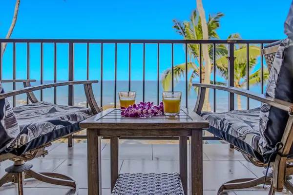 Comfortable balcony seating area with two armchairs and a table overlooking the ocean. 🌴