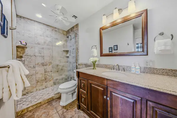 Spacious bathroom layout featuring a large wooden vanity, mirror, and toilet. 🧼