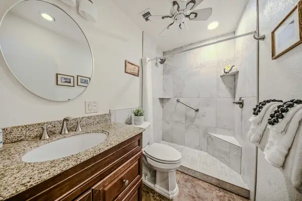 Full bathroom layout featuring a wooden vanity, oval mirror, and a clean shower/tub combo. 🧼