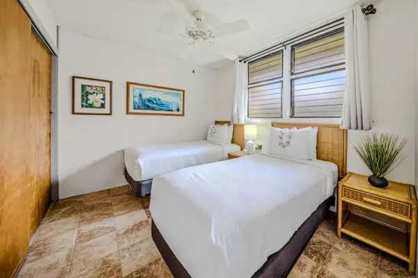 Spacious guest bedroom layout featuring comfortable beds, a nightstand, and framed wall art. 🛏️