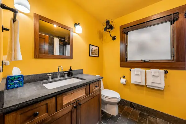 Tiled bathroom features a wooden vanity, mirror, and modern fixtures