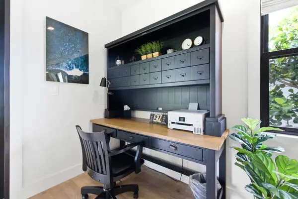 An organized home office workspace features a large dark wooden desk with a hutch