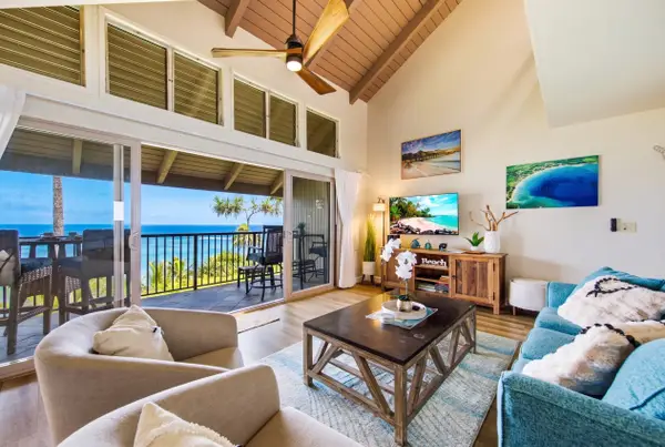 Airy living room features comfortable seating, tropical artwork, and natural light