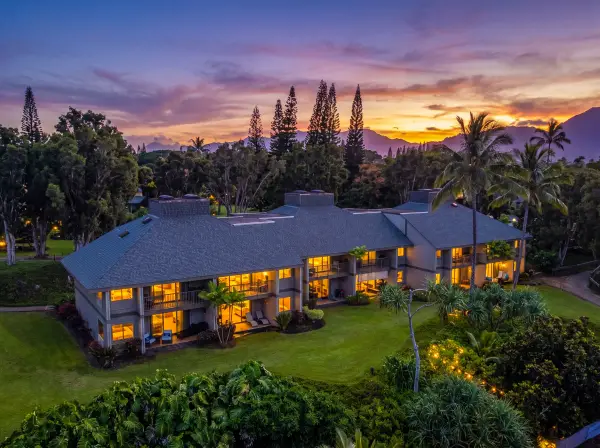 Evening property view glows warmly against mountains, gardens, and ocean