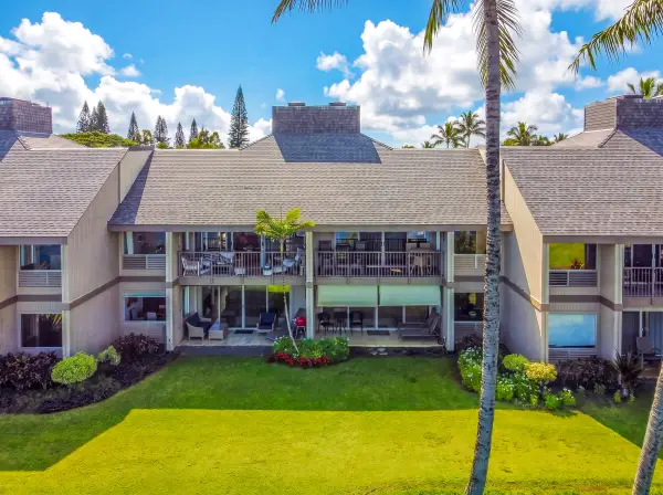 Home exterior stands surrounded by lawns, palms, and colorful gardens