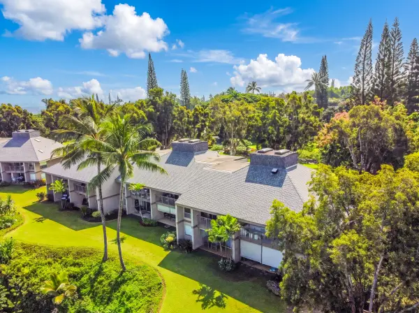 Welcoming home facade features balconies, landscaped borders, and scenic surroundings