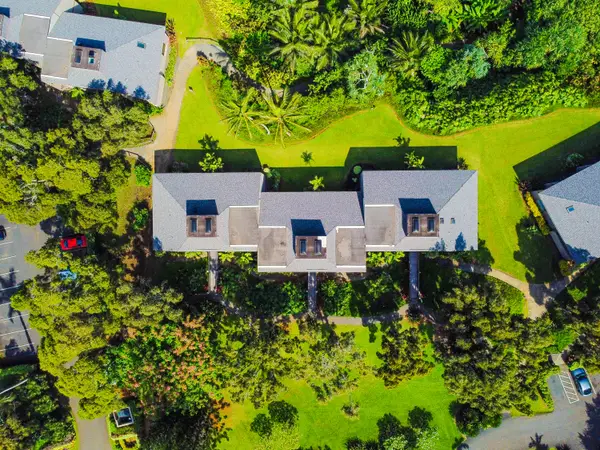 Wide aerial exterior captures the home, lush grounds, and ocean