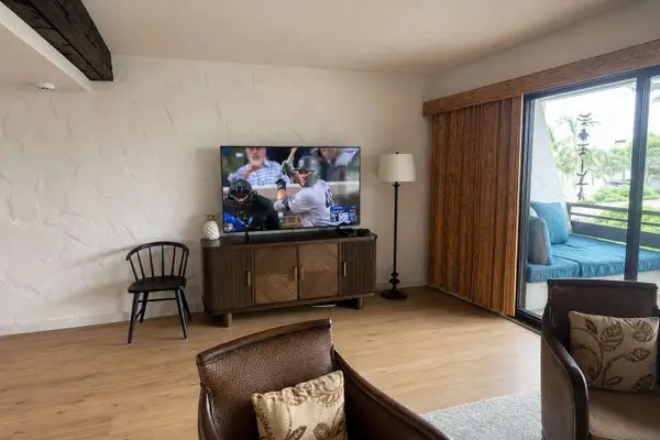 Bright living room features comfortable seating with a TV and balcony access