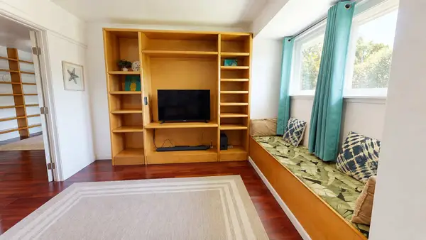 This side of the rec room features a large wooden entertainment center with built-in shelving alongside a window bench.