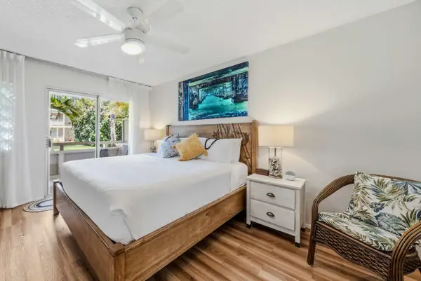 Master bedroom with plush King bed, ceiling fan, accent chair & private patio access