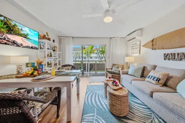 Bright living room with plush sofa, TV, surfboard decor & patio access