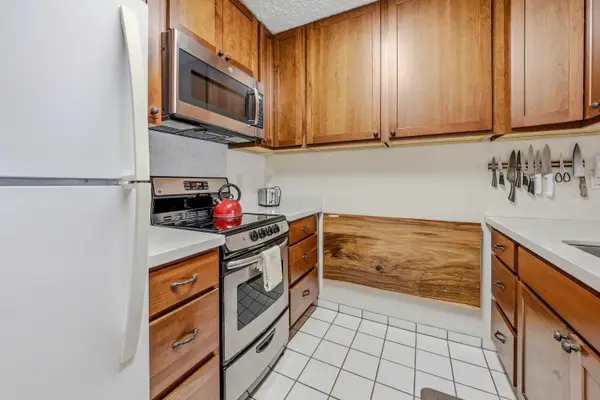Kitchen layout with full-size refrigerator, microwave, stove & wood cabinets