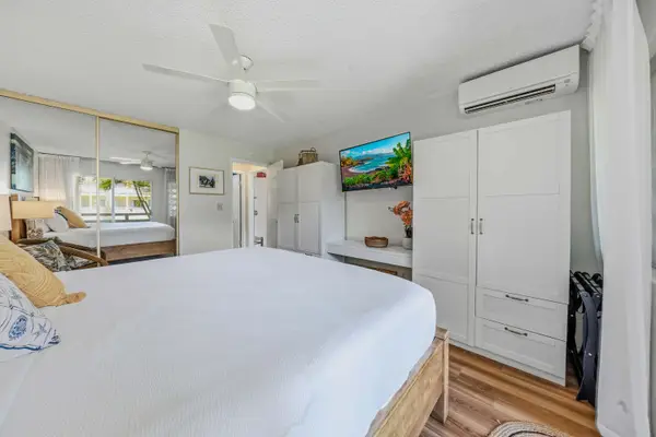 Bedroom view featuring king bed, white wardrobe, split A/C & wall-mounted TV