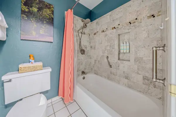 Bathroom tub and shower combination with stone tile surround & pink curtain