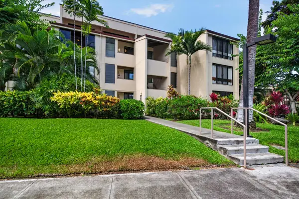 Condo building exterior with paved walkways and lush greenery