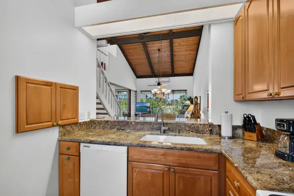 Open-concept kitchen with breakfast bar overlooking vaulted living space